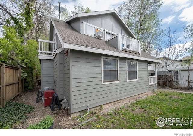 back of house with a balcony, fence, a shingled roof, and cooling unit