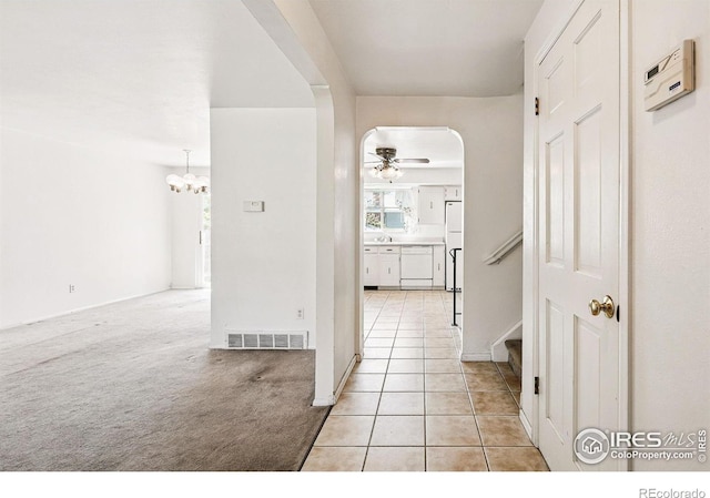 corridor with arched walkways, light tile patterned floors, stairway, and a chandelier
