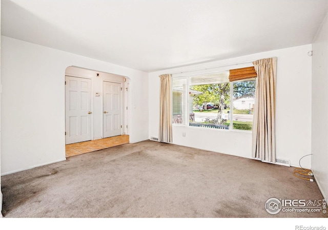 carpeted spare room with arched walkways