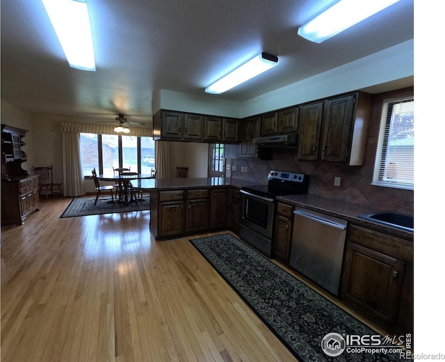 718 Linda St, Fort Morgan, CO 80701 - kitchen with appliances with stainless steel finishes, under cabinet range hood, dark countertops, light wood-type flooring, and a sink