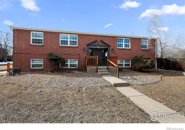 split foyer home featuring fence and brick siding
