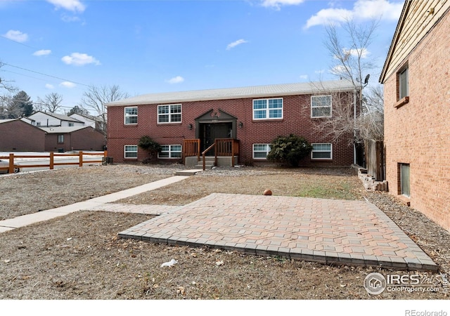 view of front of house with brick siding, fence, and a patio