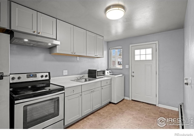 kitchen featuring washer / dryer, under cabinet range hood, appliances with stainless steel finishes, a sink, and light countertops