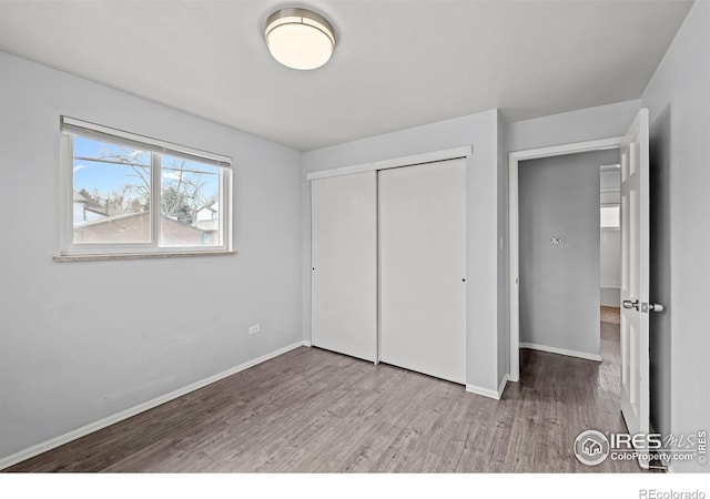 unfurnished bedroom with wood finished floors, baseboards, and a closet