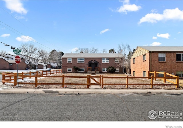split foyer home with a fenced front yard and brick siding