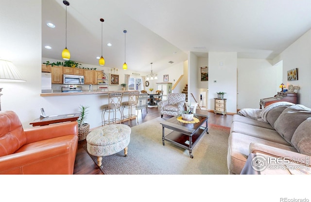 living area with vaulted ceiling, wood finished floors, stairway, and recessed lighting