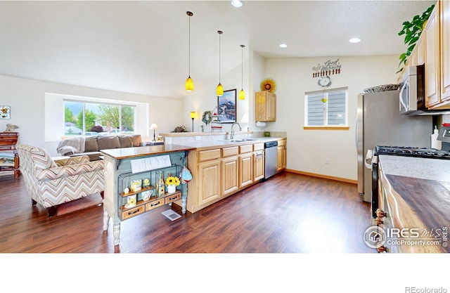 kitchen featuring stainless steel appliances, dark wood-type flooring, vaulted ceiling, a peninsula, and a sink