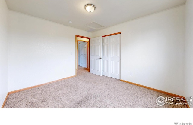 spare room featuring carpet, baseboards, and attic access