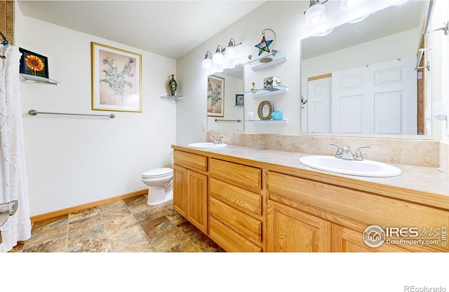 full bathroom with toilet, double vanity, baseboards, and stone finish floors