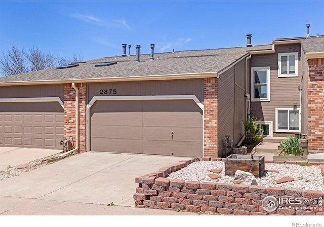view of front of property featuring brick siding, driveway, and roof with shingles