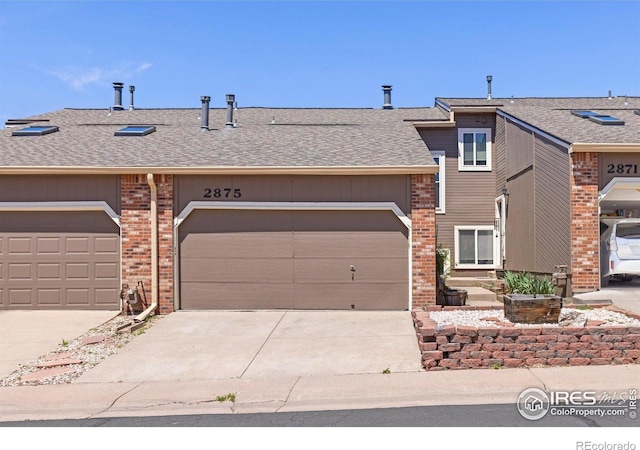 view of front of house with concrete driveway, brick siding, a shingled roof, and an attached garage