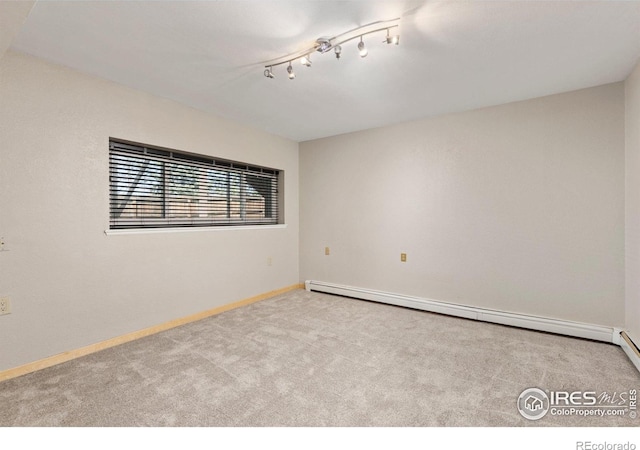 spare room featuring carpet floors, a baseboard radiator, baseboards, and rail lighting