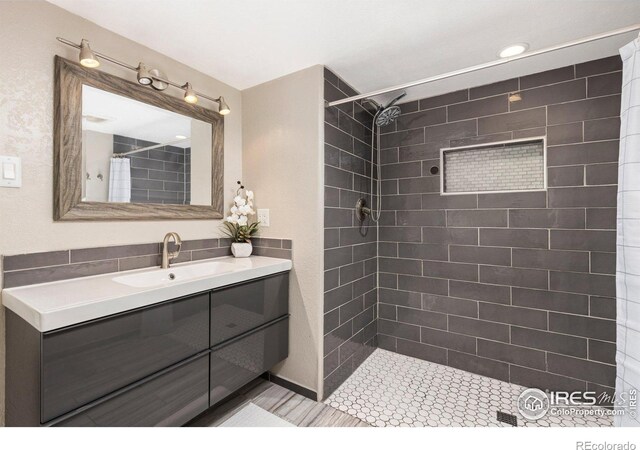 full bath featuring tiled shower and vanity