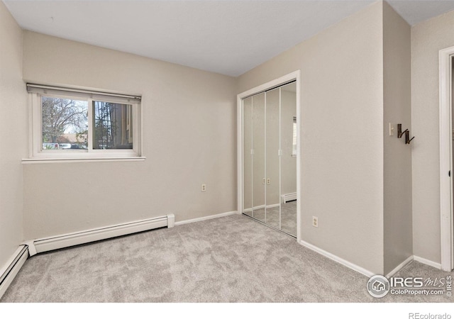 unfurnished bedroom featuring carpet, a baseboard heating unit, baseboards, and a closet