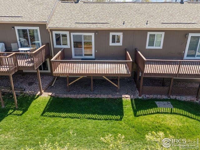 rear view of property featuring a yard, a wooden deck, and a shingled roof