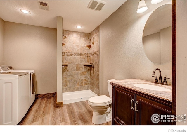 3530 Homestead Dr, Mead, CO 80542 - bathroom featuring washer and dryer, toilet, wood finished floors, tiled shower, and vanity
