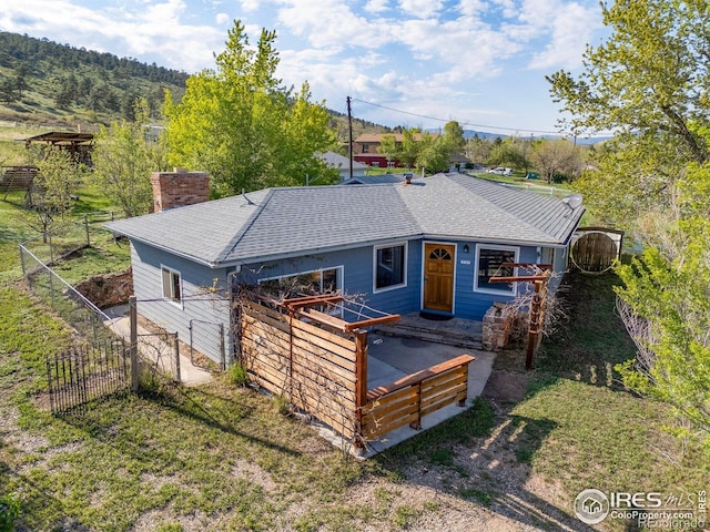 view of front of home with roof with shingles, a chimney, fence, and a deck