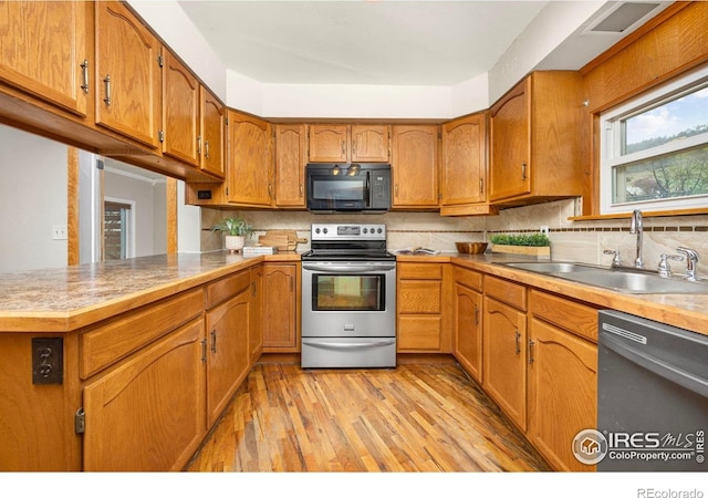 kitchen with stainless steel appliances, a sink, brown cabinetry, light wood finished floors, and tasteful backsplash