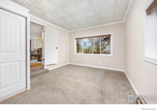 carpeted spare room with baseboards and an ornate ceiling
