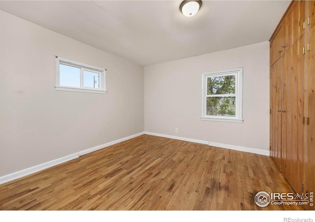 unfurnished bedroom with light wood-style flooring, baseboards, and a closet