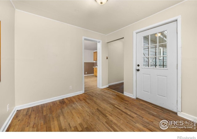 spare room with crown molding, hardwood / wood-style flooring, and baseboards