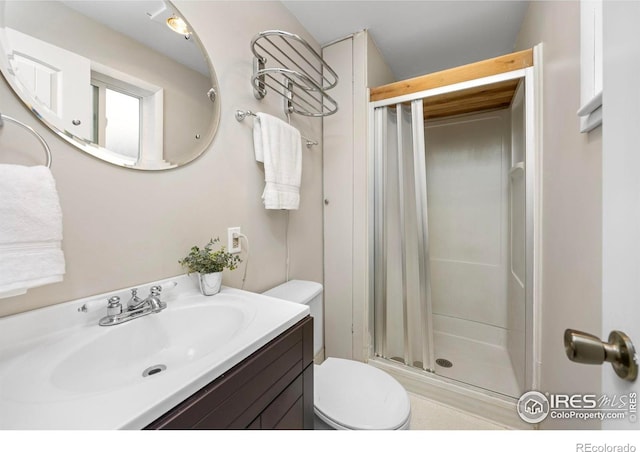 bathroom with a shower stall, toilet, and vanity