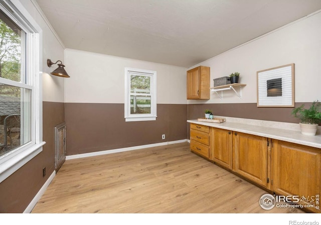 kitchen featuring light wood finished floors, brown cabinets, open shelves, light countertops, and baseboards