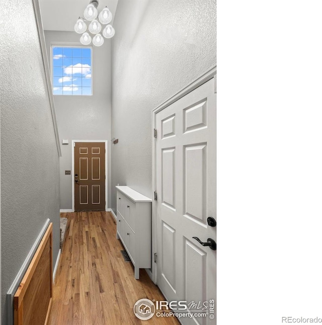 2002 E 102nd Cir, Thornton, CO 80229 - doorway with light wood-style flooring, a chandelier, a textured wall, and baseboards