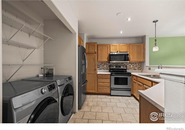 2002 E 102nd Cir, Thornton, CO 80229 - kitchen featuring stainless steel appliances, a sink, washing machine and clothes dryer, tasteful backsplash, and pendant lighting