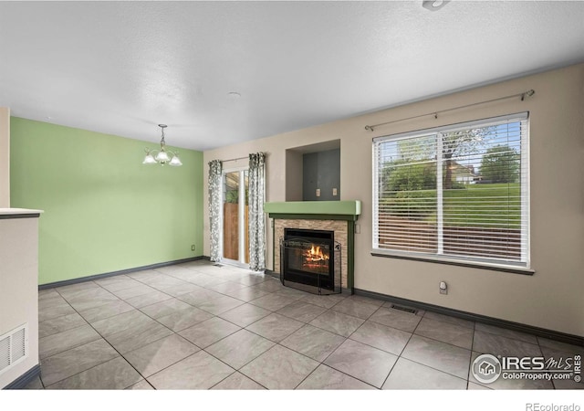 2002 E 102nd Cir, Thornton, CO 80229 - unfurnished living room featuring a chandelier, a glass covered fireplace, a textured ceiling, light tile patterned floors, and baseboards