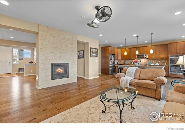 living area featuring light wood-style floors, recessed lighting, a fireplace, and baseboards
