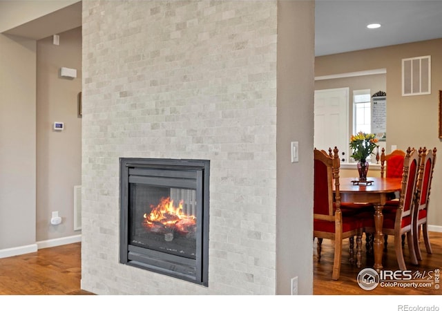detailed view of wood finished floors, baseboards, a multi sided fireplace, and recessed lighting
