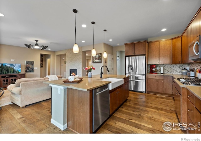 kitchen featuring stainless steel appliances, a sink, wood-type flooring, open floor plan, and recessed lighting