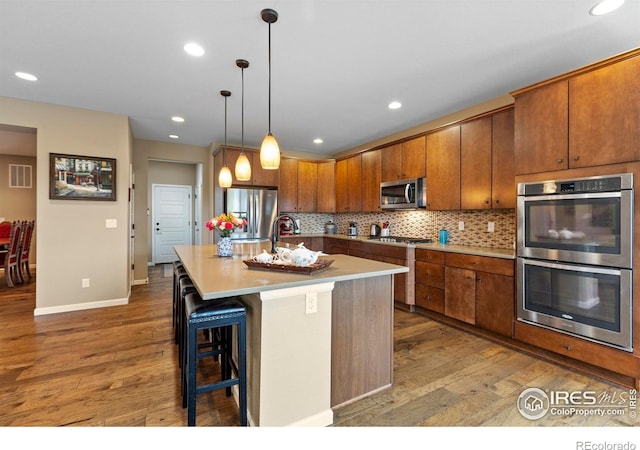 kitchen with stainless steel appliances, hardwood / wood-style flooring, baseboards, decorative backsplash, and recessed lighting