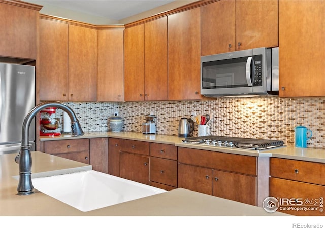 kitchen featuring stainless steel appliances, a sink, light countertops, and tasteful backsplash