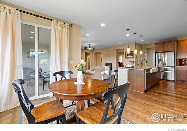 dining area with light wood-style floors, a fireplace, and recessed lighting