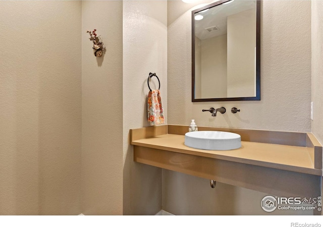 bathroom featuring a sink and a textured wall