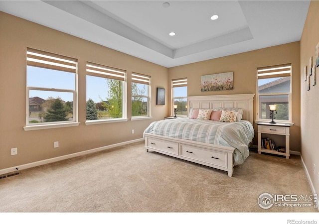 carpeted bedroom with baseboards, recessed lighting, and a raised ceiling