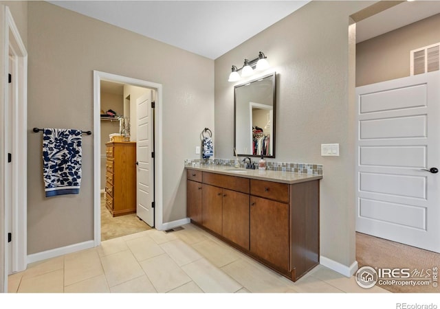 bathroom featuring vanity, baseboards, and a walk in closet