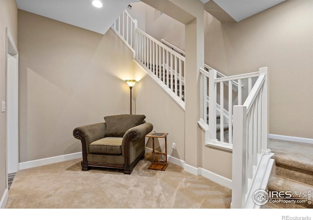 living area with carpet flooring, stairs, and baseboards