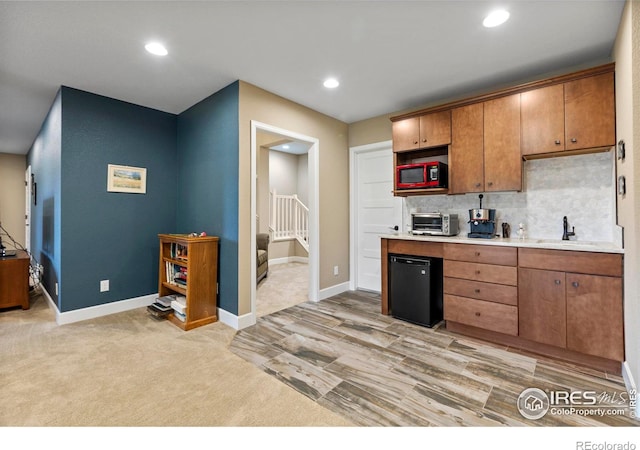 kitchen featuring a sink, decorative backsplash, baseboards, recessed lighting, and light countertops