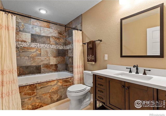 bathroom featuring toilet, tiled shower / bath, vanity, and a textured ceiling