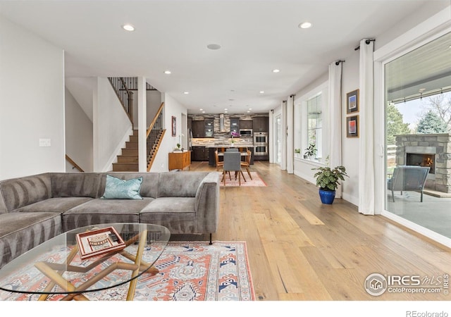 living room with recessed lighting, light wood-style flooring, stairway, a fireplace, and baseboards