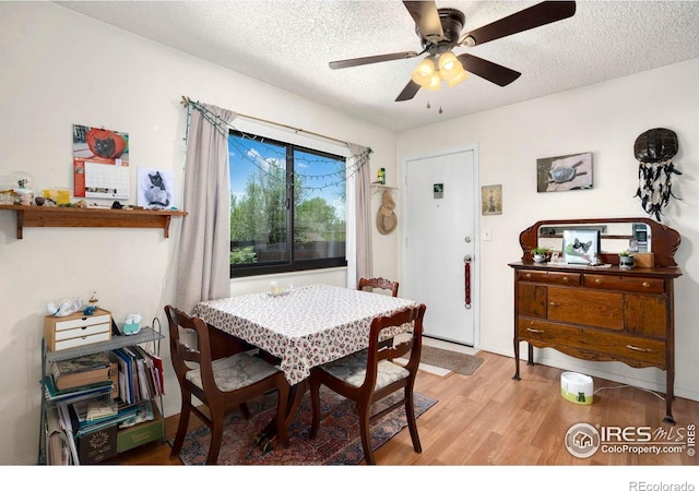 dining area with light wood-style flooring, a textured ceiling, and ceiling fan