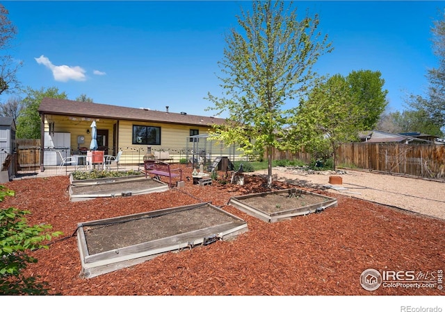 rear view of house with a vegetable garden and fence
