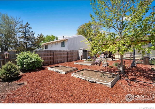 fenced backyard with a garden, a storage shed, and an outdoor structure