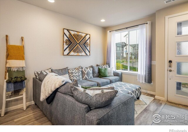 living area featuring light wood-style floors, baseboards, and recessed lighting