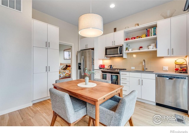 725 Amelia Ln, Lafayette, CO 80026 - kitchen with stainless steel appliances, a sink, light wood-style flooring, white cabinetry, and open shelves