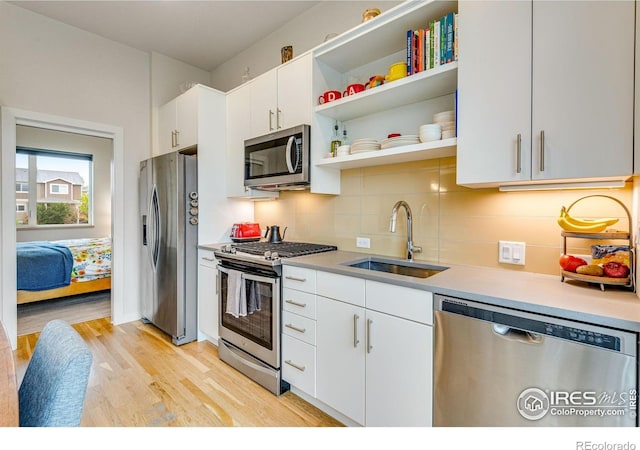 725 Amelia Ln, Lafayette, CO 80026 - kitchen featuring stainless steel appliances, a sink, light wood-type flooring, tasteful backsplash, and white cabinetry