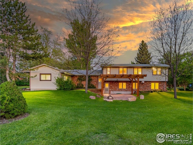back of property at dusk featuring a pergola, a patio, a yard, and brick siding